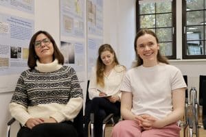 im Konferenzraum des IEG, drei junge Frauen sitzen im Publikum auf Stühlen und hören einem Vortrag zu
